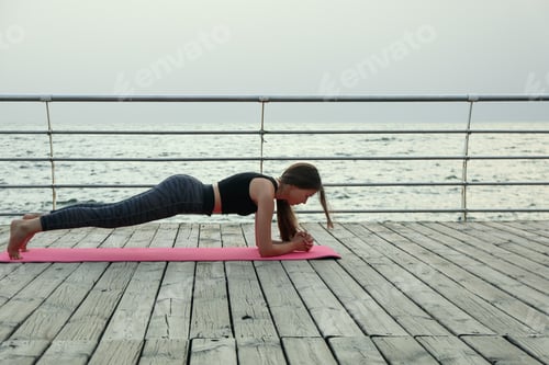 Preview: Young woman on yoga mat on wooden floor outdoors, space for text