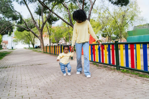 Preview: A woman is holding a baby in her arms while walking down a path