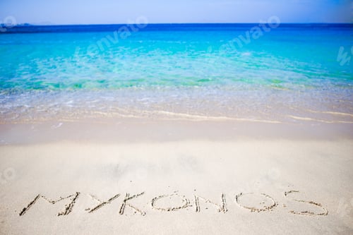 Preview: Word Mykonos handwritten on sandy beach with soft ocean wave on background