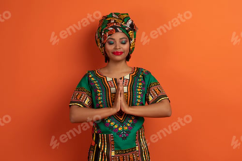 Preview: Peaceful calm young black woman meditating on orange
