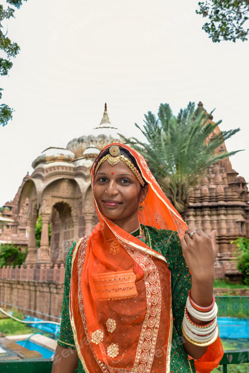 Preview: Indian Woman with beautiful face and orange sari posing with ruins in background
