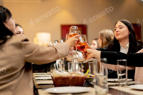 Preview: work colleagues in a restaurant celebrating conclusion of a new deal toast with glasses of wine