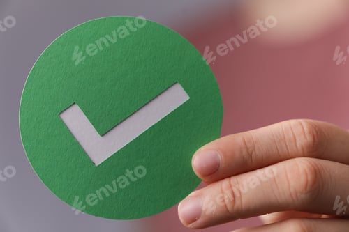 Preview: Closeup shot of a person's hand holding a green checkmark