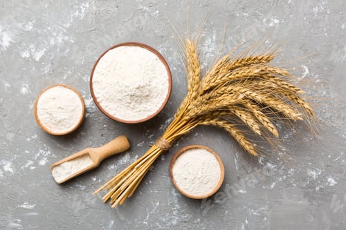Preview: Flat lay of Wheat flour in wooden bowl with wheat spikelets on colored background
