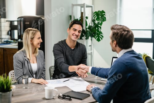 Preview: Happy couple shaking hands with their real estate agent at home.