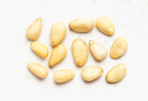 Preview: several shelled pine nuts close up on gray