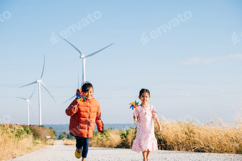 Preview: Two children girl with pinwheel playfully run by windmills