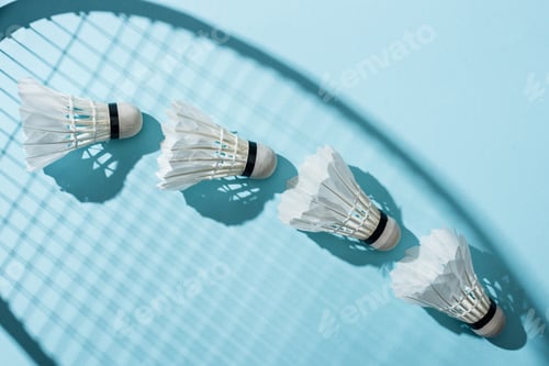 Preview: top view of shuttlecocks near shadow of badminton racket on blue