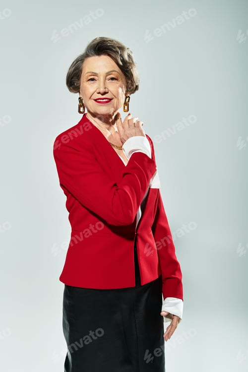 Preview: A beautiful woman in her 60s poses confidently in elegant attire, showcasing her style and grace.