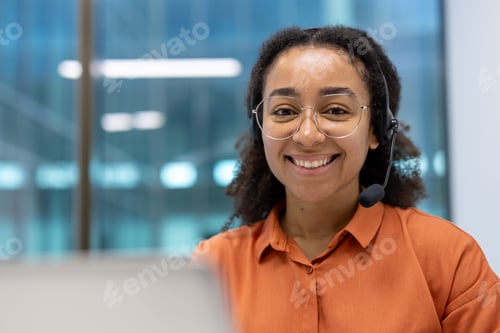Preview: Confident young African American businesswoman smiling in office environment wearing headset