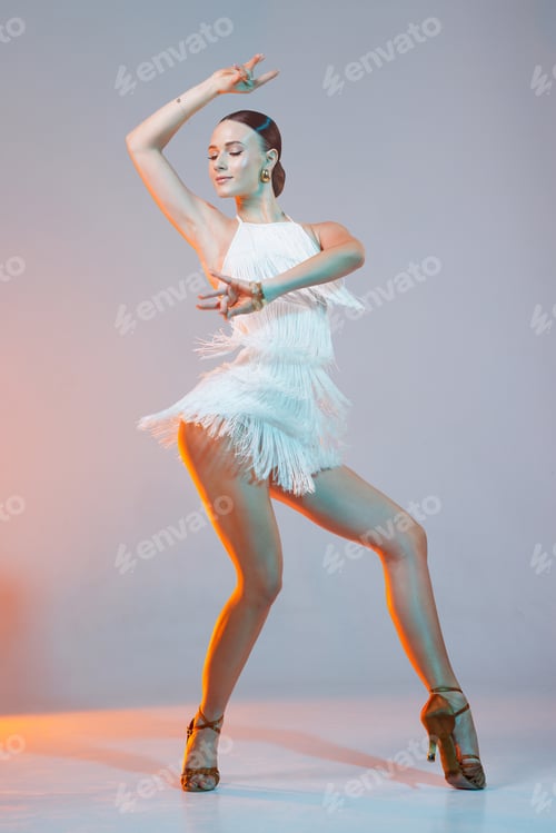Preview: Confident Latin dancer performing stylish movement in white fringe costume