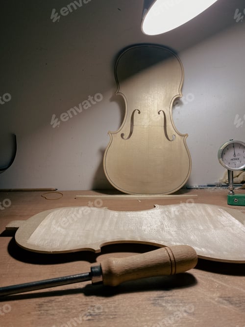 Preview: raw new violin top plate and back plate carving on violin maker desk and tools