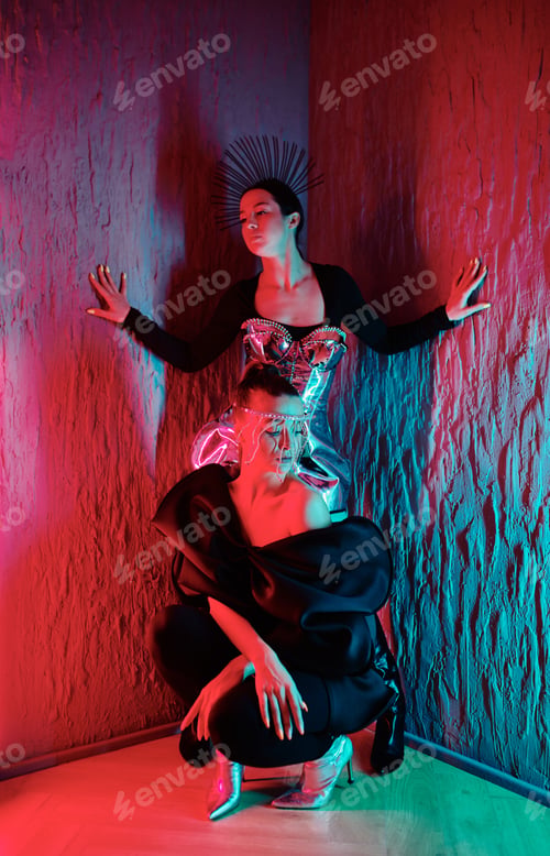 Preview: Two posh teenage girls in surreal stage apparel standing in the corner of studio
