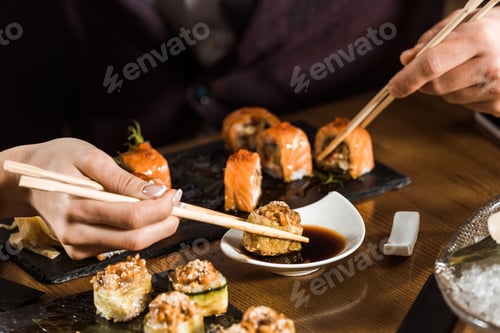 Preview: Cropped view of people eating sushi with chopsticks in restaurant