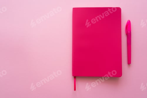 Preview: top view of bright notebook and pen on pink