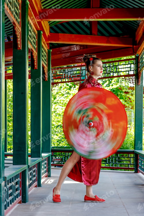 Preview: A young Asian girl walks in national clothes with umbrella. Chinese woman in a red traditional dress