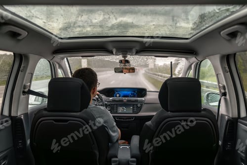 Preview: Driving in rainy weather. Modern car interior. Rear seat perspective.