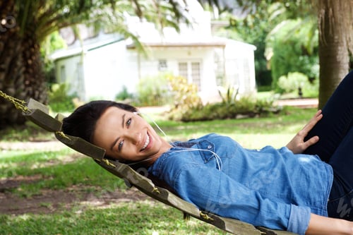 Preview: Amiling woman relaxing outside listening to music