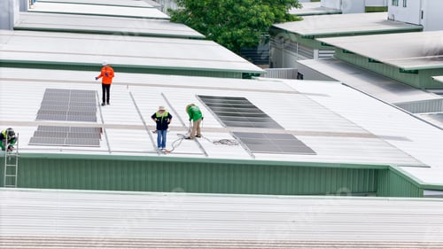 Preview: Aerial view of a rooftop with solar panels, showing a technician in safety performing maintenance.