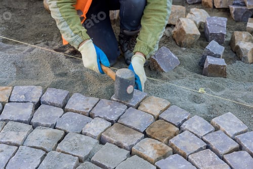 Preview: The worker were using industrial cobblestones to pave the sidewalk with granite stones.