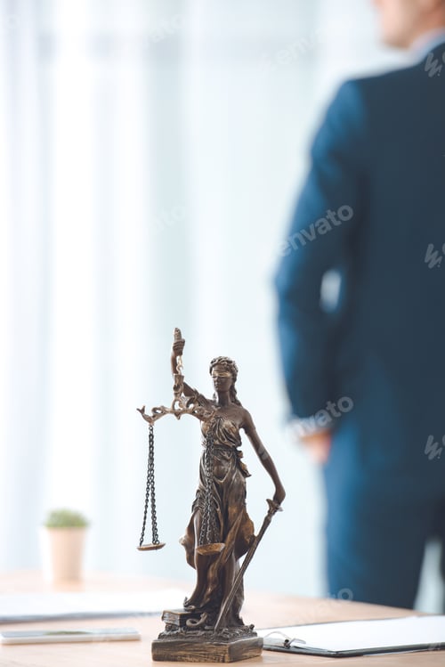 Preview: close-up view of lady justice statue and lawyer standing behind