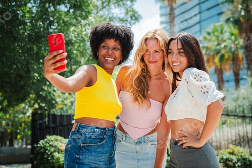 Preview: Three Diverse Young Women Taking a Fun Selfie Together with a Smart Phone, Showcasing Friendship