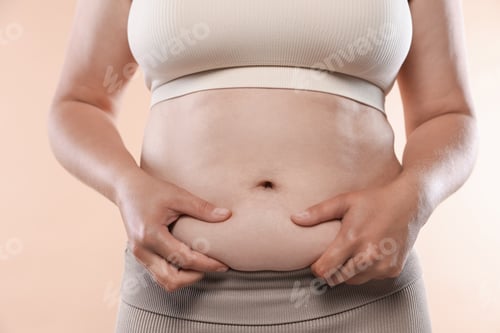Preview: Woman with excessive belly fat on beige background, closeup. Overweight problem