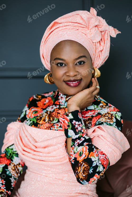 Preview: African woman with bright makeup and stylish jewerly, wearing colorful pink dress and ethnic