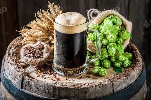 Preview: Dark beer with foam on old barrel. Brewing industry.