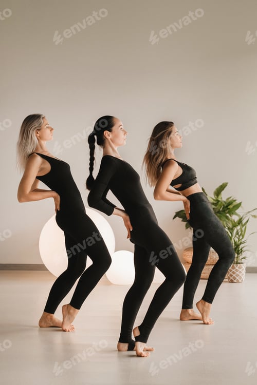 Preview: A group of girls in black doing yoga poses indoors. Women are engaged in fitness