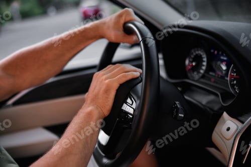 Preview: Close up of hands gripping a modern car steering wheel while driving on a city street