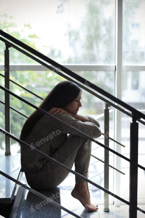 Preview: Depressed young woman sitting on stairs