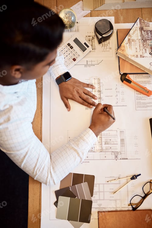 Preview: High angle shot of an architect using a ruler to draw a building plan