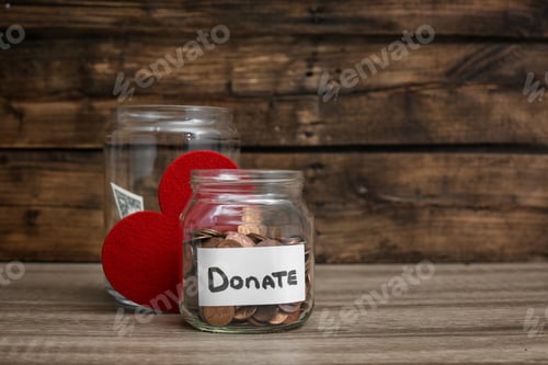 Preview: Donation jars with money and red heart on table. Space for text