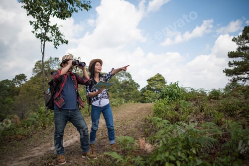 Preview: Two Young Traveler with backpack, are holding map relaxing in greens jungle Summer vacations.