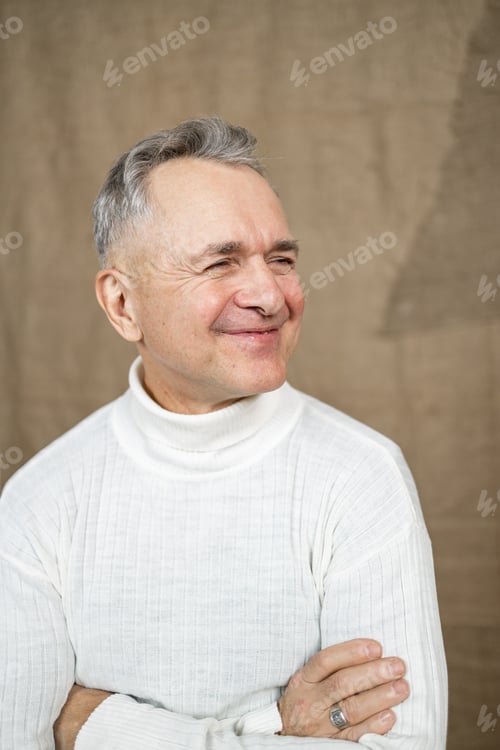 Preview: Portrait of a happy senior man smiling against beige background.