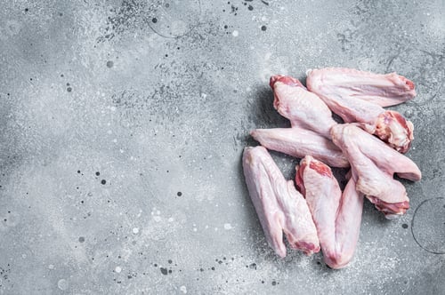 Preview: Fresh raw duck wings on kitchen table. Gray background. Top view. Copy space