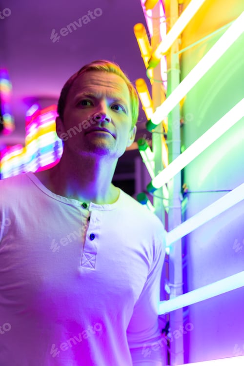 Preview: Man in white shirt looking into the distance in front of neon lights