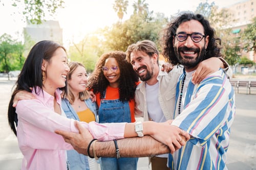 Preview: Group of joyful young adult friends embracing each others on a social gathering outdoors, having fun