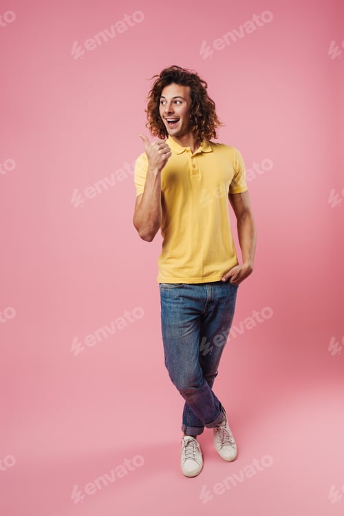 Preview: Happy handsome caucasian guy smiling and pointing finger aside