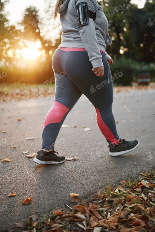 Preview: Curvaceous young woman training, neck down view walking in park