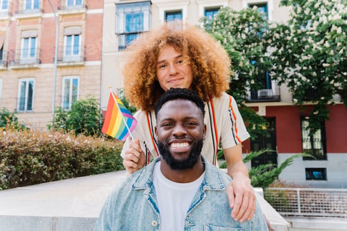 Preview: Two men hugging, holding rainbow flag, celebrating lgbtq pride