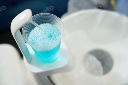 Preview: Glass with disinfectant solution for by patient in modern dental office
