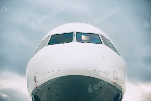 Preview: Front view of the airplane nose against cloud sky.