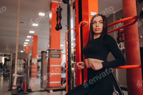 Preview: Laughing woman with curly hair sits on the floor in the gym on the background of the partition.