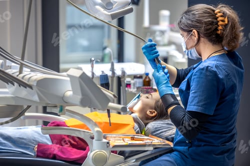 Preview: Young female dentist in dental office. Dentist at work. Dental treatment concept.