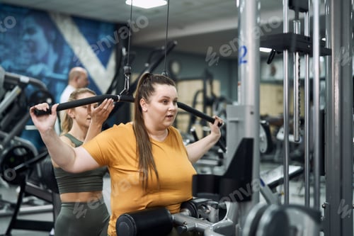 Preview: Caucasian woman with overweight training at the gym