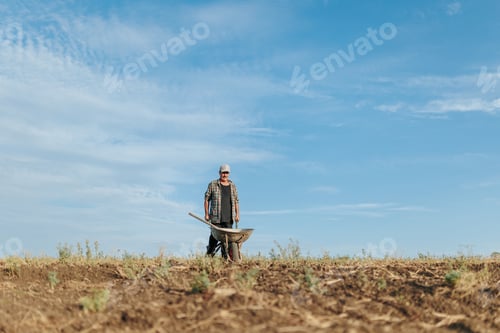 Preview: Elderly Worker Walking with Wheelbarrow on Country Road