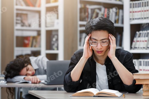 Preview: Two tired students studying in the university library