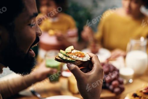 Preview: Close-up of black man eating healthy sandwich at home.
